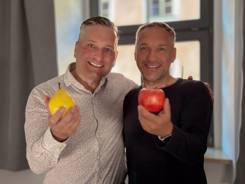 Dirk und Frank Gröschel präsentieren einen Apfel und eine Birne vor der Kamera, um die Metapher des Beitrags visuell zu untermauern.