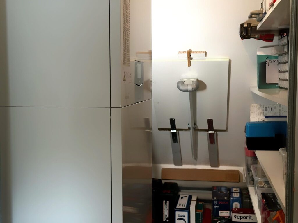 Blick in den kleinen Heizraum der Dachzentrale, in der die Inneneinheit der Luft-Wasser-Wärmepumpe installiert ist.