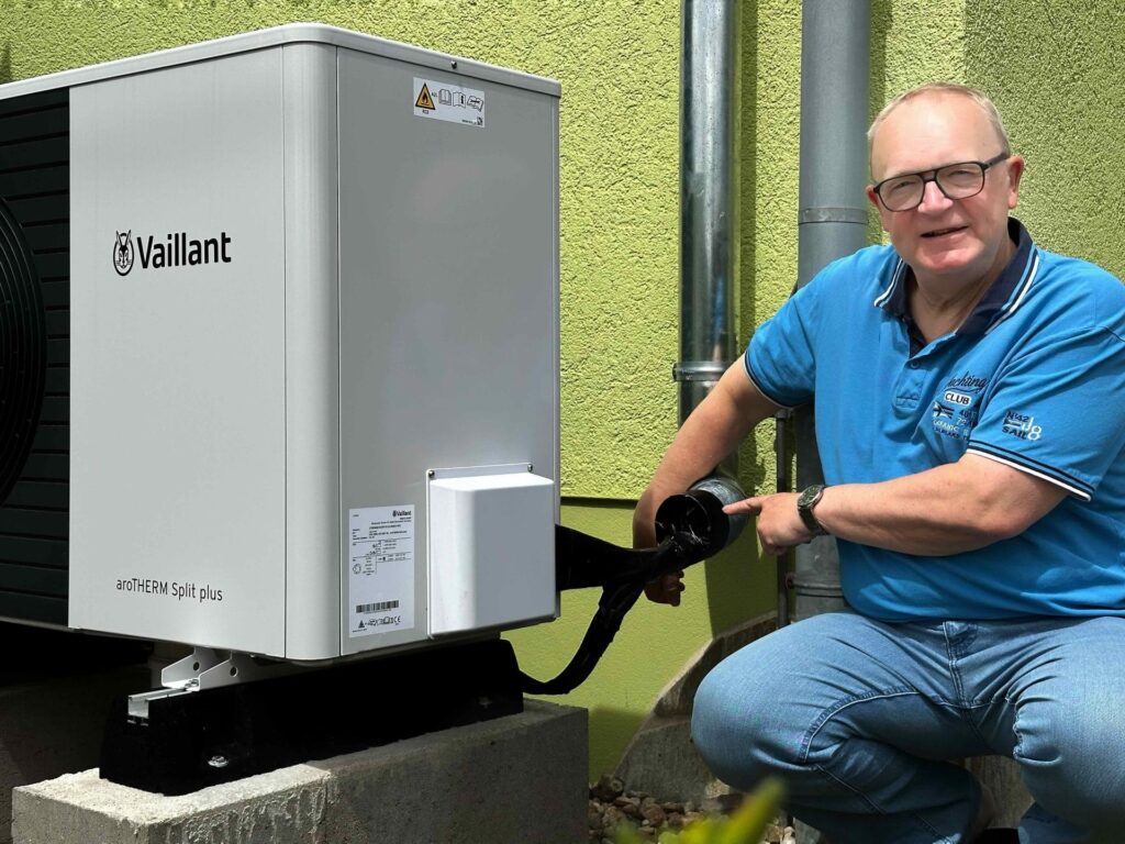Holger Schleife aus Bannewitz zeigt, wie die Führung der Kältemittelleitungen und Elektroverbindungen seiner neuen Luft-Wasser-Wärmepumpe Vaillant aroTHERM-Split in das separate Regenfallrohr integriert worden ist.