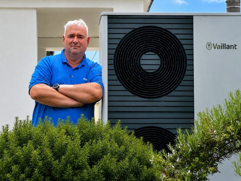 Chris Engelhardt aus Freital neben der Außeneinheit seiner Luft-Wasser-Wärmepumpe Vaillant aroTHERM plus